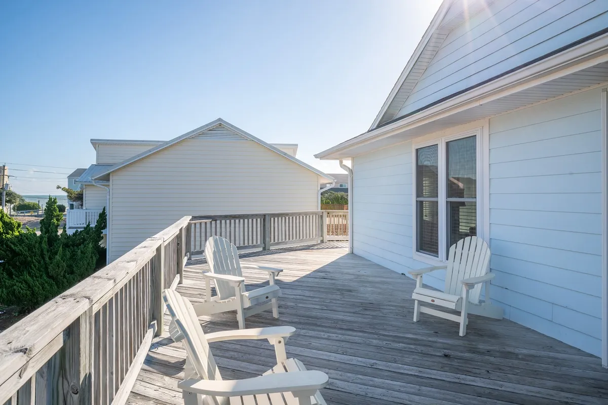 An inviting deck features classic Adirondack chairs and a wide-open view, suggesting a perfect spot to unwind after a day spent sightseeing or enjoying outdoor adventures. The open space and deck railing connect visually to the outdoors, reinforcing a sense of exploration and relaxation.