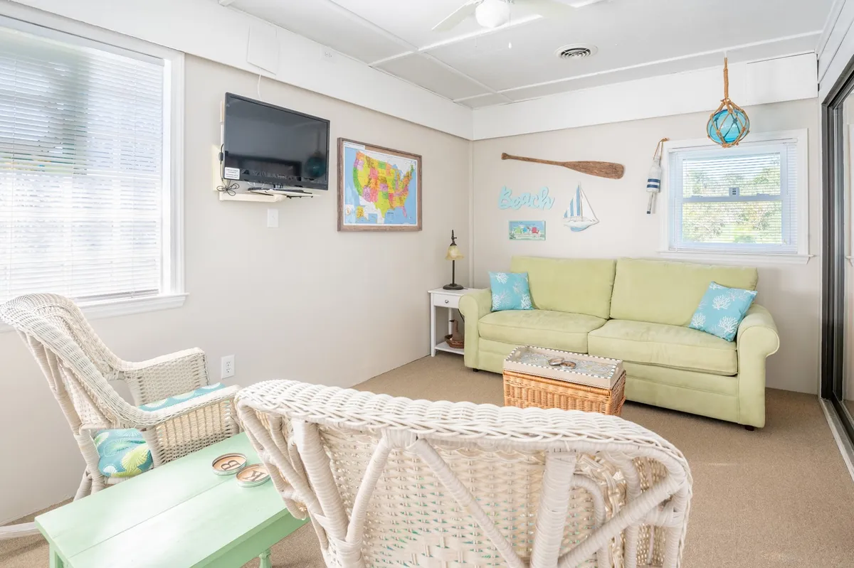 A cheerful, casual living area with a green sofa, woven chairs, beach-themed decor, and a decorative paddle and map, fostering a playful and relaxed atmosphere ideal for socializing or planning the next local adventure.